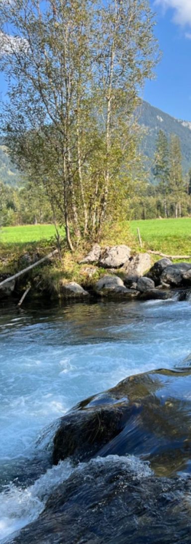 go-beyond-retreat-fluss-bewegung-balance.jpg Flusslandschaft mit klarem Wasser und Bergen im Hintergrund – Symbol für Balance, innere Ruhe und natürliche Bewegung im Go Beyond Retreat